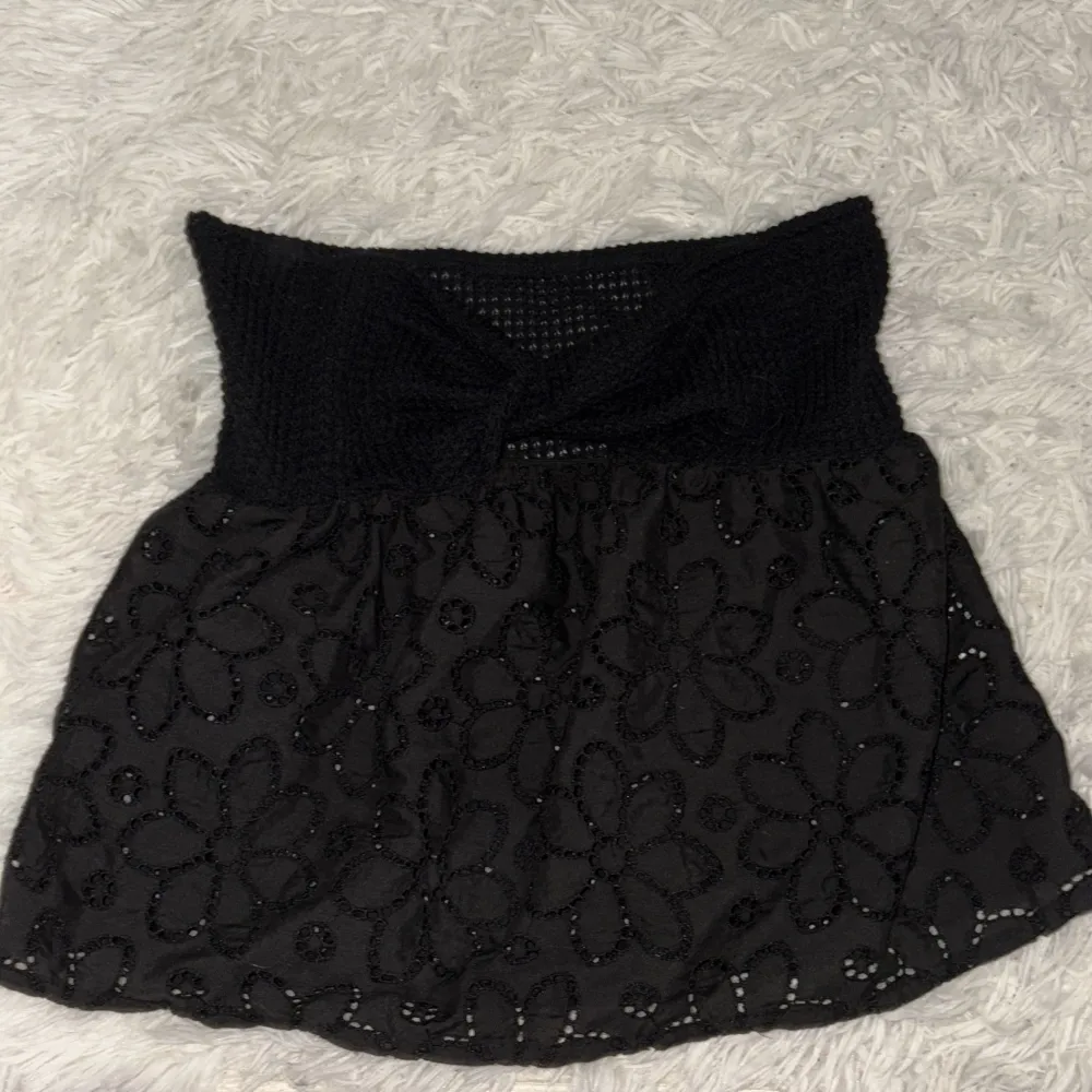 Snygg svart topp med blommönster och utsvängd midja. Toppen har en fin struktur och är perfekt för att ge en stilfull look. Den är mellan lång och passar bra till olika tillfällen.. Yläosat.