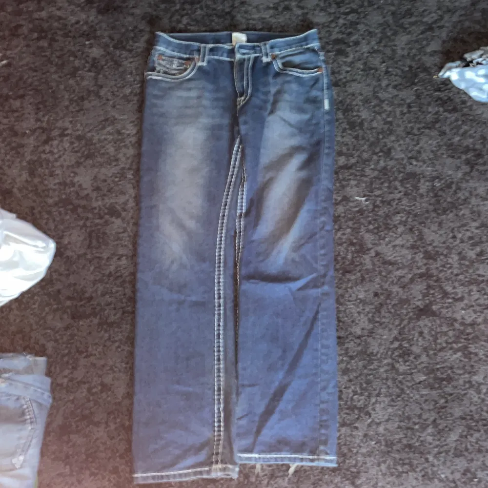 Snygga blå jeans med tydliga kontrastsömmar och klassisk femficksdesign. De har en rak passform och är perfekta för en avslappnad stil. Detaljer som knappar och slitningar ger en cool look. saknar en knapp, OBS: ACCEPTERA INTE TILLBAKA SKICKNINGAR . Farkut & Housut.