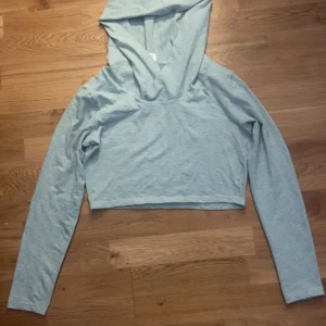 Ljusblå croppad hoodie - Säljer en ljusblå croppad hoodie med långa ärmar. Perfekt för en avslappnad stil. Tillverkad i en mjuk blandning av bomull, polyester och lycra. Passar bra till jeans eller leggings för en casual look. Storlek L (Barnstorlek). 
