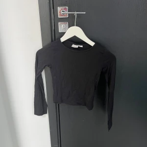 Svart långärmad topp - Säljer en stilren svart långärmad topp. Perfekt för att matcha med olika outfits. Toppen har en enkel design och är ett mångsidigt plagg i garderoben.
