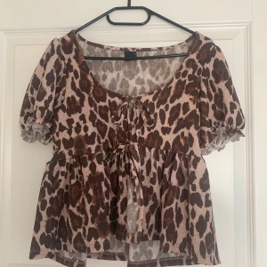 Leopardmönstrad blus med knytning - Leopardmönstrad blus med korta puffärmar. Använd fåtal gånger 