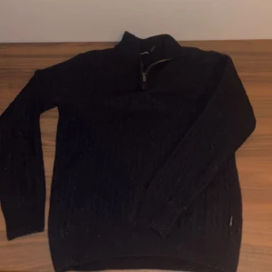 Mörkblå stickad tröja från Sand  - Snygg mörkblå stickad tröja från Sand med dragkedja i halsen. Perfekt för kyligare dagar med sitt stilrena och klassiska utseende. Tröjan har långa ärmar och en ribbad krage som ger extra komfort. Köpt på Nk kvittot kan visas privat Pris kan diskuteras 