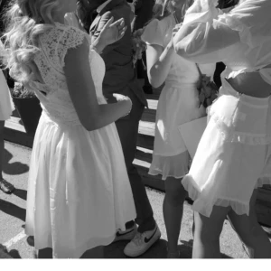 Vit spetsklänning med öppen rygg - Charmig vit klänning med spetsdetaljer och en vacker öppen rygg. Klänningen har en v-ringad design och korta ärmar. Endast använd en gång.