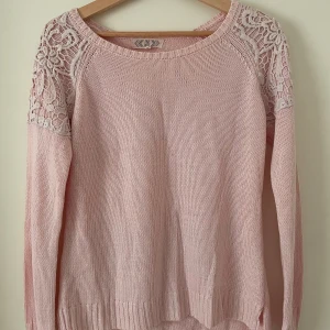 Rosa stickad tröja med spetsdetaljer från Pink Rose - Säljer en söt rosa stickad tröja från Pink Rose med vackra spetsdetaljer på axlarna. Tröjan har långa ärmar och är tillverkad i en mjuk bomulls- och akrylblandning. Perfekt till sommar och vår!😍🌸🌸Den är liten i storleken så skulle säga att den matchar S/XS bättre!