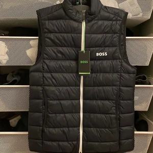 Svart väst - Boss - Snygg svart quiltad väst från Boss med dragkedja framtill. Perfekt för att hålla värmen med stil. Boss-logga på bröstet och ryggen ger en exklusiv touch. Aldrig använd och säljer för att jag aldrig hann returnera inom 14 dagar.      Nypris: 2400kr                                                        Mitt pris: 1499