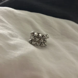 Äkta Silvrig Edblads ring med nitar mm: 16.80 - Snygg Edblad ring i silverfärg med flera nitar som ger en tuff look. Perfekt för att addera lite attityd till din stil. Ringen har en bred design och är tillverkad i metall.