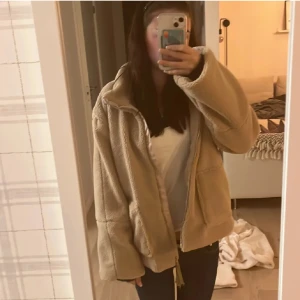 Beige teddyjacka - Mysig beige teddyjacka med dragkedja framtill. Jackan har en avslappnad passform och långa ärmar, perfekt för kyligare dagar. Den fluffiga texturen ger en trendig look.jääte fin🥰