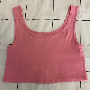 Rosa croppad linnetopp - Säljer en söt rosa croppad linnetopp. Perfekt för varma sommardagar. Toppen är ärmlös och har en enkel design som gör den lätt att matcha med olika outfits.