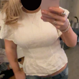Vit blus med volangdetaljer - Säljer en söt vit blus, som går tajtare i midjan. Från H&M säljs inte längre. Säljer pga att den är för liten. Storlek XS