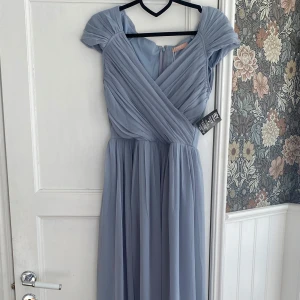 Blå balklänning  - Ljusblå balklänning från Nelly i storlek 34. Klänningen är helt oanvänd, lappar finns kvar på. Dragkedja finns i ryggen, som referens är jag 166 och den blir perfekt med klackar.