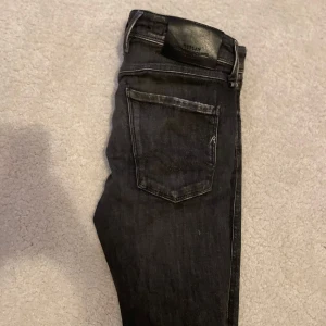 Svarta jeans från Replay - Snygga svarta jeans från Replay med en klassisk femficksdesign. De har en smal passform och är perfekta för en stilren look. Jeansen har en knappgylf och är tillverkade i ett stretchigt material för extra komfort.