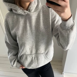 Grå hoodie - Säljer en klassisk grå hoodie med känguruficka och justerbar huva. Perfekt för en avslappnad stil. Passar bra till jeans eller träningsbyxor.