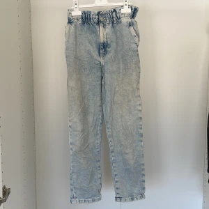 Ljusblå jeansbyxor med resårmidja - Snygga ljusblå jeansbyxor med en bekväm resårmidja. Byxorna har en avslappnad passform och raka ben, vilket ger en skön och trendig look. Perfekta för en casual stil.