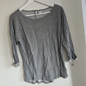 Grå långärmad tröja från H&M - Säljer en enkel och bekväm grå långärmad tröja från H&M. Perfekt för en avslappnad stil med rund hals och mjukt material. Passar bra till jeans eller leggings. Hör av dig vid intresse!