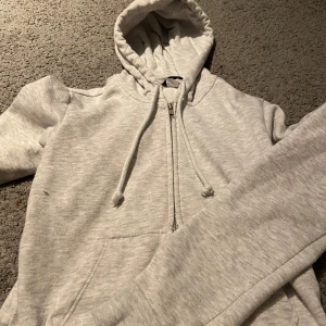 Grå hoodie från H&M - Säljer en bekväm grå hoodie från H&M med dragkedja och justerbar huva. Perfekt för en avslappnad stil. Den har långa ärmar och är tillverkad i mjukt material för extra komfort.