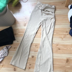 Beige byxor från Lindex - Säljer ett par bekväma beige byxor från Lindex. Byxorna har en hög midja och vida ben, vilket ger en avslappnad och stilren look. Perfekta för en casual dag ute eller hemma.