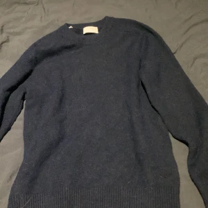 Mörkblå stickad tröja från Selected Homme - Säljer en stilren mörkblå tröja från Selected Homme. Tröjan är långärmad och har en klassisk rund halsringning. Perfekt för kyligare dagar och kan enkelt matchas med olika outfits.