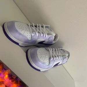 Nike Air Force i vitt och lila - Snygga Nike Air Force sneakers i vitt och lila. Skorna har en klassisk design med snörning och en lila sula som ger en cool kontrast. Perfekta för en stilren look. Kan tänka mig att gå ner i pris vid snabb affär!