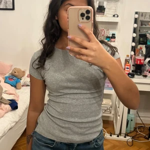Grå t-shirt - Säljer en enkel och stilren grå t-shirt med korta ärmar. Perfekt för en avslappnad look. Passar bra till jeans eller shorts. Storlek 158/164 men vääääldigt stretchig så skulle säga passar xxs-m