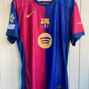 Lamine Yamal - FC Barcelona 2024/25 - FC Barcelonas matchtröja från årets säsong 2024/25 med Lamine Yamal. Rep. Aldrig använd.  Tröjan är en player verison. Bättre kvalité men tajtare i passformen. Storleken motsvarar mer large än XL. 