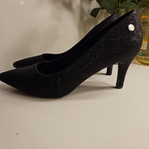 XTI Pumps, Svarta, Storlek 40 nytt - Oanvända Eleganta svarta pumps från XTI. Perfekta för festliga tillfällen eller för att piffa upp vardagsoutfiten. Klassisk design med spetsig tå och klack. Klackhöjd 6. Nypris 699 kr
