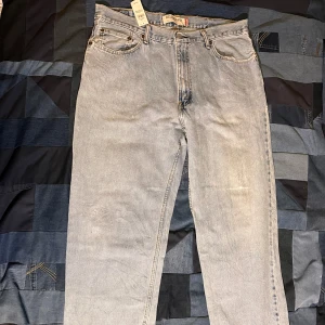 Ljusblå jeans från Levi's - Säljer ett par ljusblå jeans från Levi's med relaxed fit. Klassisk design med fem fickor och knappgylf. Perfekta för en avslappnad stil. Lagom många slitningar, totala längd: 101cm och midjans längd tvärs över: 46cm, benöppning: 22cm