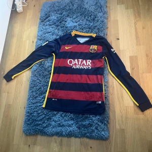 FC Barcelona långärmad fotbollströja - Säljer en långärmad FC Barcelona tröja från Nike. Tröjan har de klassiska blå och röda ränderna med gula detaljer. Den har klubbens emblem på bröstet och sponsorerna Qatar Airways och Unicef tryckta på framsidan och baksidan.