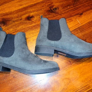 Grå Chelsea boots i mockaimitation - Snygga grå Chelsea boots i mocka med elastiska sidopaneler för enkel på- och avtagning. Perfekta för en stilren look och passar bra till både jeans och klänning. Helt nya!
