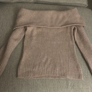 Beige ribbad offshoulder tröja från H&M - Säljer en snygg gammel rosa ribbad offshoulder tröja från H&M. Perfekt för en stilren look med långa ärmar och en bekväm passform. Passar utmärkt till både jeans och kjol. Hör av dig vid intresse!