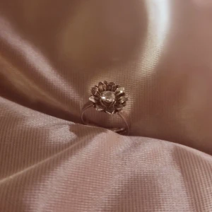 Silverring med blomdesign - Elegant silverring med en vacker blomdesign. Ringen har en detaljrik blomma med en glittrande sten i mitten. Ringens storlek går att justera. Äkta vintage. 💗