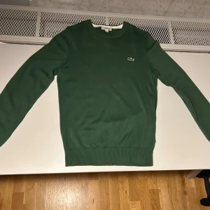Lacoste finstickad kofta - Riktigt snygg finstickad Lacoste kofta.  Använd ett fåtal gånger, i nyskick.  Storlek XS. Perfekt till hösten.
