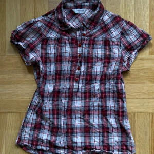 Rutig kortärmad blus från Topshop - Superfin rutig blus från Topshop i rött, svart och vitt! Kortärmad och fina knappar framtill. Storlek 12 enligt etiketten, skulle gissa att den är S.