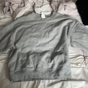 Grå sweatshirt - Säljer en enkel och stilren grå sweatshirt. Den är perfekt för en avslappnad look och passar till det mesta. Tröjan har långa ärmar och en ribbad kant vid ärmslut och nederkant. Använd endel gånger men ingen fläck på den.