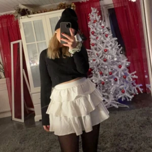 Vit volangkjol - Säljer en superfin vit volangkjol som är perfekt för festliga tillfällen. Kjolen har flera lager av volanger som ger en härlig volym och rörelse. Den är kort och passar perfekt till både vardag och fest. Kjolen kan ha små defekter men inga märkbara!