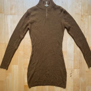 Brun ribbad klänning från Han Kjøbenhavn S - Säljer en stilren brun ribbad klänning från Han Kjøbenhavn. Tröjan har en dragkedja framtill och en hög krage som ger en snygg look. Perfekt för kyligare dagar.