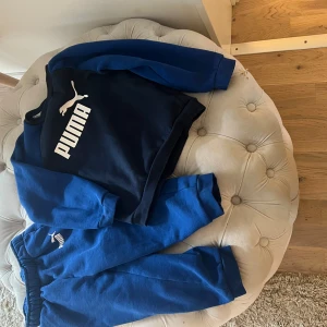 Blå och marinblå tröja från Puma - Säljer en snygg blå och marinblå tröja från Puma med deras ikoniska logga i vitt på bröstet. Tröjan har långa ärmar och en sportig look, perfekt för en avslappnad stil.