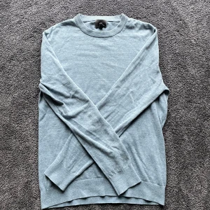 Ljusblå tröja från H&M - Säljer en stilren ljusblå tröja från H&M i slim fit. Tröjan är långärmad och har en rund halsringning med ribbade kanter. Perfekt för en avslappnad och snygg look. Storlek M