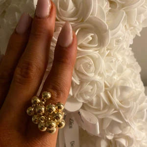 Guldfärgad ring med klusterdesign - Elegant guldfärgad ring med en unik klusterdesign av små kulor. Perfekt för att ge en lyxig touch till din outfit. Passar utmärkt för speciella tillfällen.