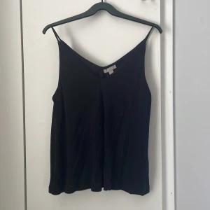 Svart topp - Svart linnetopp med smala axelband och v-ringning. Perfekt för en sommaren och enkel look. Passar bra till både jeans och kjol.