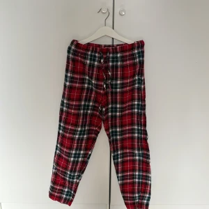 Rutiga pyjamasbyxor - Säljer ett par mysiga röd- och grönrutiga pyjamasbyxor med snörning i midjan. Perfekta för en avslappnad dag hemma. Storlek 146/152. Aldrig använda pga för liten storlek, har sedan dess bara legat i garderoben.