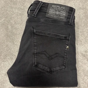 Svarta jeans från Replay - Snygga svarta jeans från Replay med klassisk femficksdesign. De har en diskret logga på bakfickan och en knappgylf. Perfekta för en stilren look. W31/L32