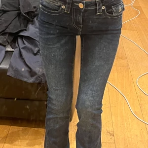 Mörkblå jeans med broderad bakficka - Snygga mörkblå jeans med broderad detalj på bakfickan. De har en tight passform och är lågmidjade, vilket ger en smickrande siluett. Perfekta för en stilren look.