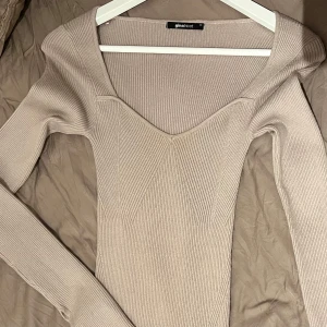 Beige ribbad klänning från Gina Tricot, XS - Långärmad klänning med en fyrkantig halsringning och en figurnära passform. Klänningen har en ribbstickad design och är från Gina tricot. Mycket bra skick, använd en dag. Storlek xs.