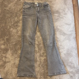 Grå bootcut jeans från Gina Tricot - Snygga grå bootcut jeans från Gina Tricot. De har en klassisk femficksdesign och stängs med dragkedja och knapp..