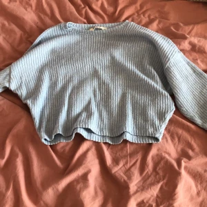 Ljusblå ribbad kofta från H&M - Säljer en ljusblå ribbad kofta från H&M. Den har en croppad passform och långa ärmar, perfekt för en avslappnad stil. Koftan är gjord i ett mjukt material som känns skönt mot huden.