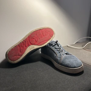 Blå sneakers med röd sula - Snygga blå sneakers i mocka med den ikoniska röda sulan från Christian Louboutin. Skorna har snörning och en stilren design med rund tå. Perfekta för dig som vill ha en touch av lyx i vardagen.              Priset kan gå ner vid snabb affär! Finns ingen skolåda.