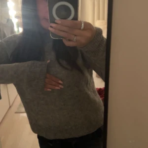 Grå stickad tröja - Mysig grå stickad tröja med långa ärmar och ribbade muddar. Perfekt för kyliga dagar och enkel att matcha med olika outfits. Säljer då jag inte använder och är som ny 