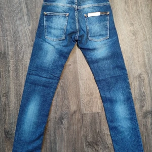 Blå jeans från Nudie Jeans - Snygga blå jeans från Nudie Jeans, modell Thin Finn. De har en klassisk femficksdesign och en dragkedja. Perfekta för en stilren look med en modern Touch. Helt nya & oanvända! 