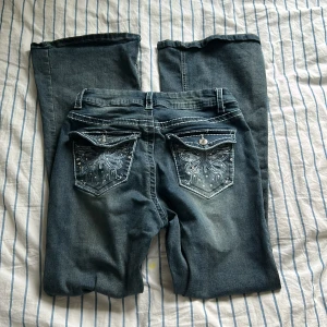 Blå jeans med broderade bakfickor - Snygga blå jeans med unika broderade detaljer på bakfickorna. De har en klassisk femficksdesign och en knappgylf. Perfekta för att ge din outfit en extra touch 💕❤️🎀