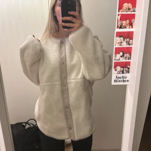 Vit teddyjacka från H&M - Mysig vit teddyjacka från H&M med knappar framtill. Jackan har en rund halsringning och långa ärmar, perfekt för kyliga dagar.  Pile Jacka  lappen sitter kvar aldrig använd 